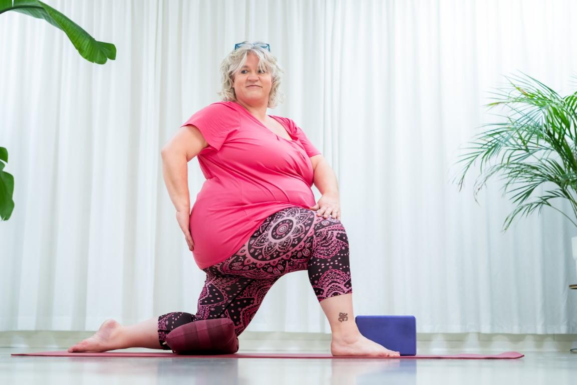 plussize yoga van een dikke yogajuf plussize yogajuf in een geknielde gedraaide yogahouding